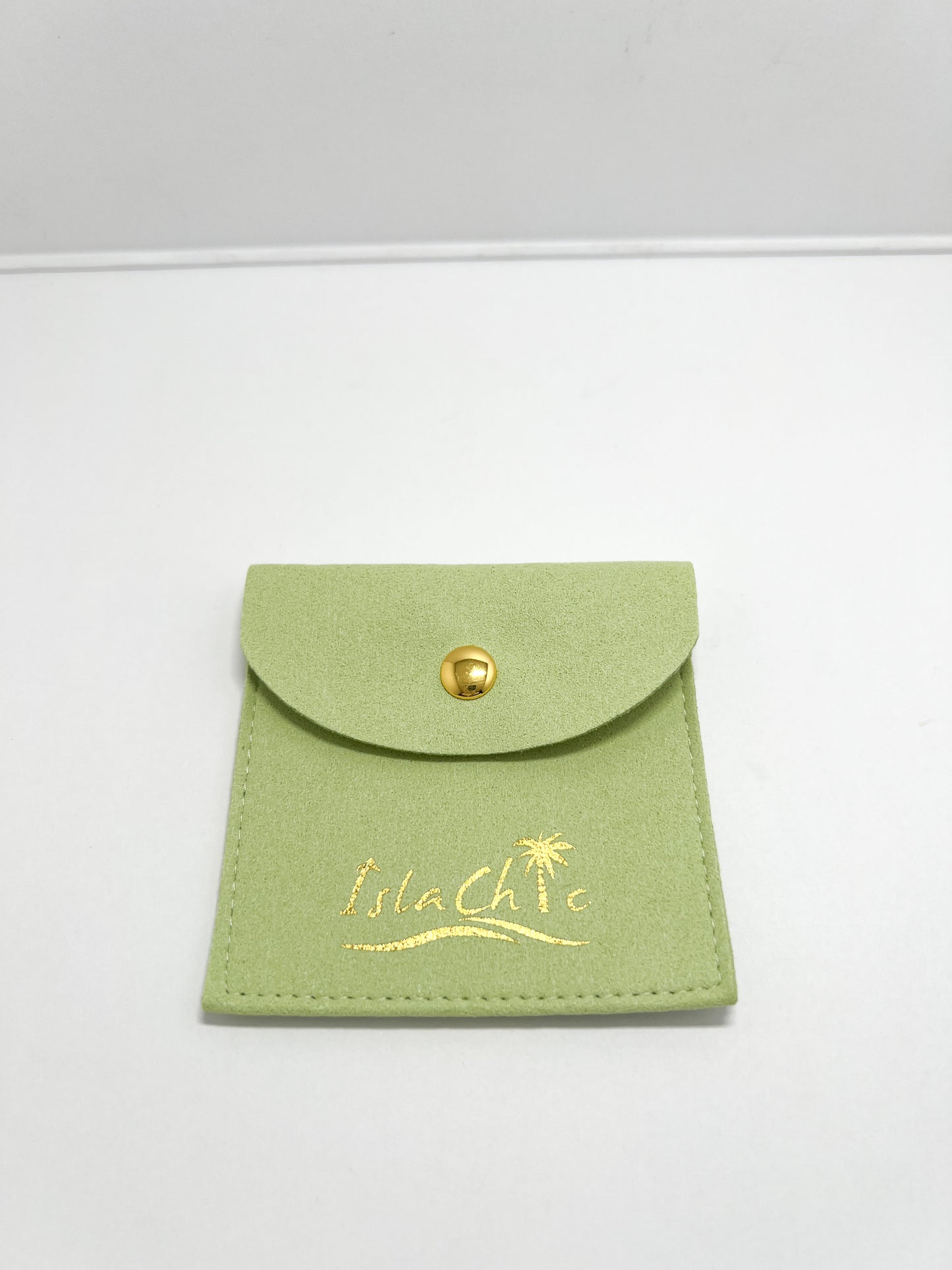 A  lime green fabric jewelry pouch with a gold snap closure and embossed IslaChic logo