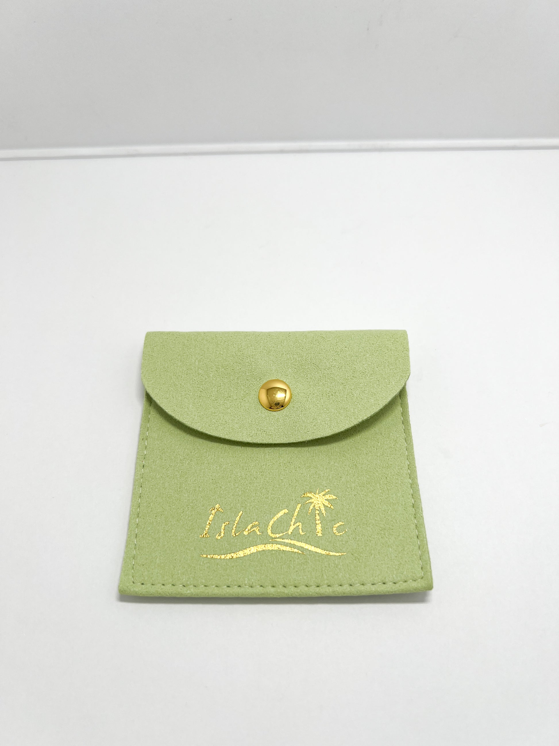 A  lime green fabric jewelry pouch with a gold snap closure and embossed IslaChic logo