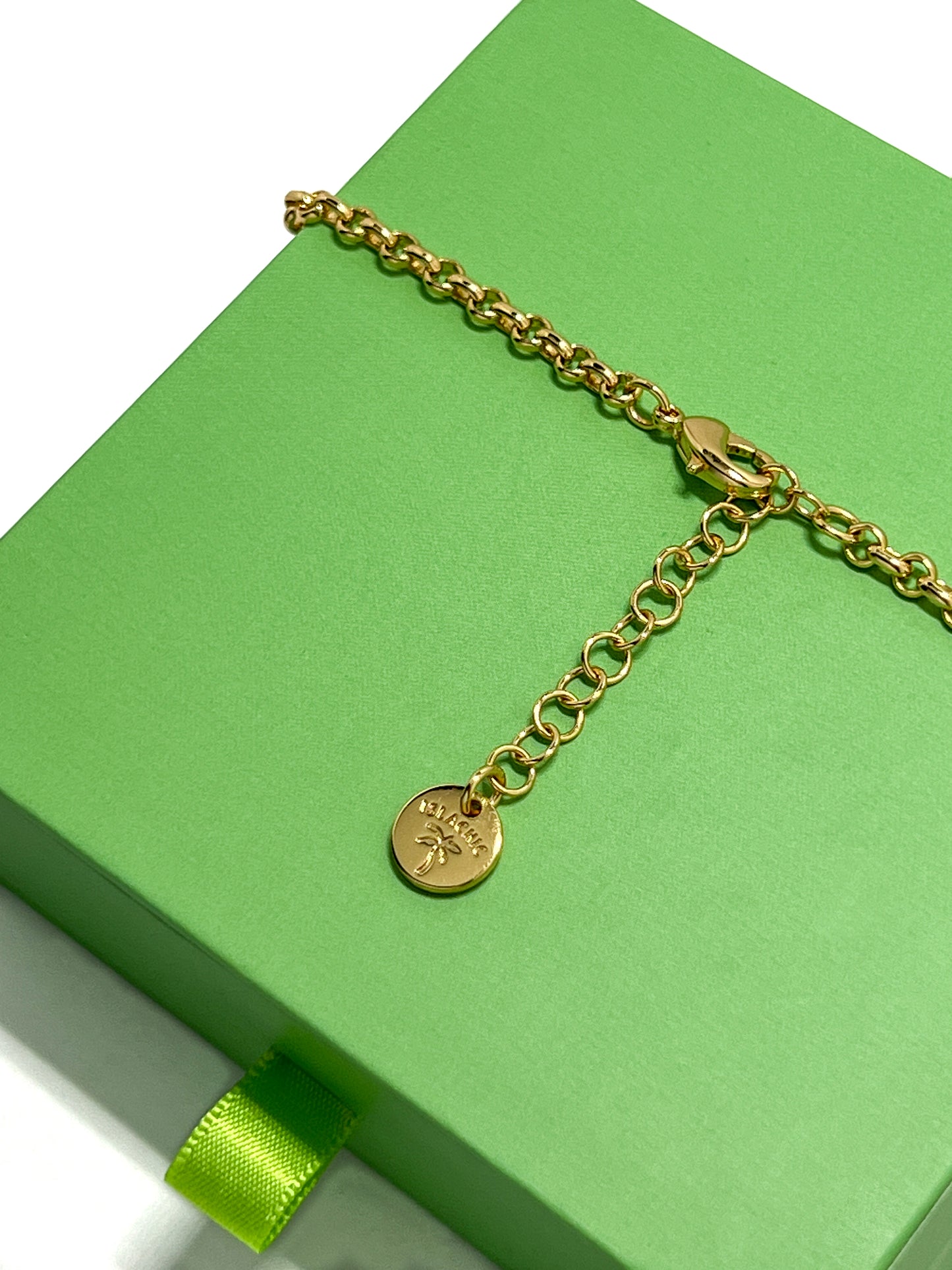 A close-up of the Lucia Necklace adjustable chain extender, showing the lobster clasp and a round gold IslaChic brand tag.