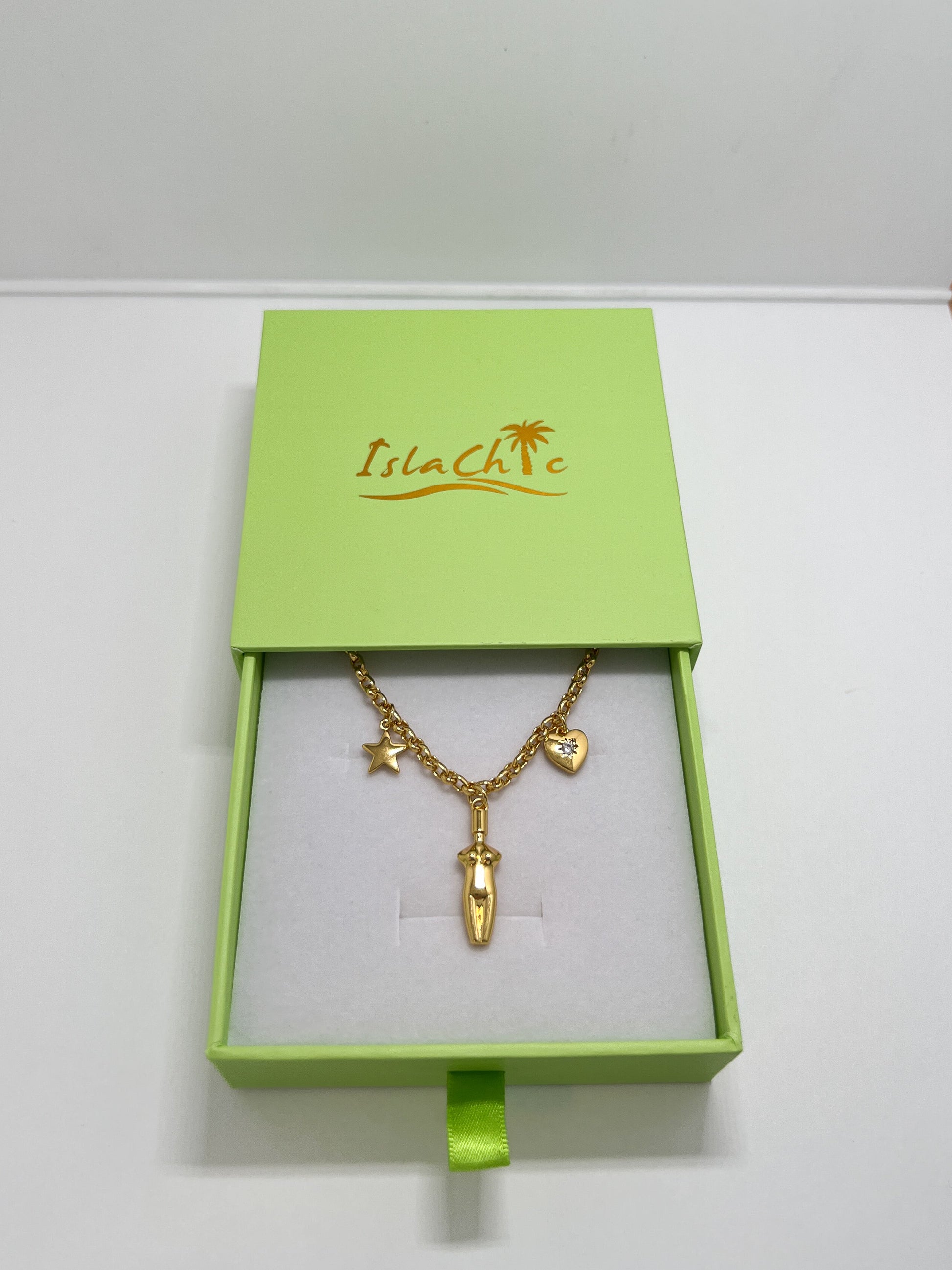 The Lucia Charm Necklace displayed inside an open lime green IslaChic gift box on a white velvet interior cushion.